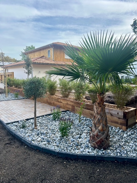 Coin détente extérieur aménagé avec pavés, galets blancs, arbustes persistants