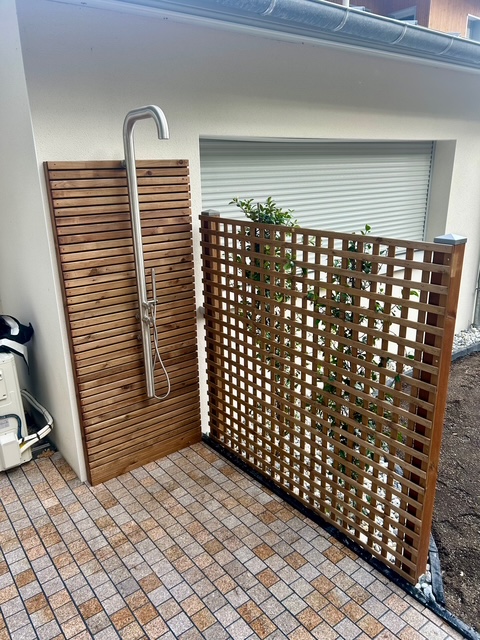 Chemin d’accès jardin avec bordures en pierre, jeunes plantations et paillage en copeaux de bois autour d’un citronnier