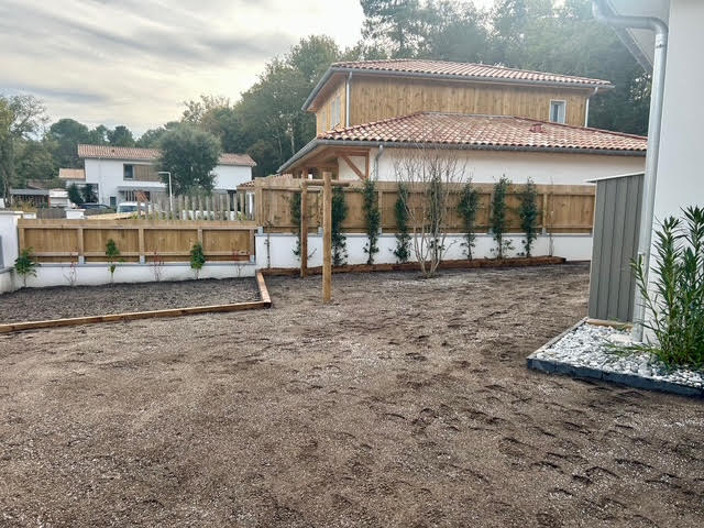 Petite terrasse extérieure en pavés autobloquants avec douche de jardin en bois et jardinière de galets décoratifs
